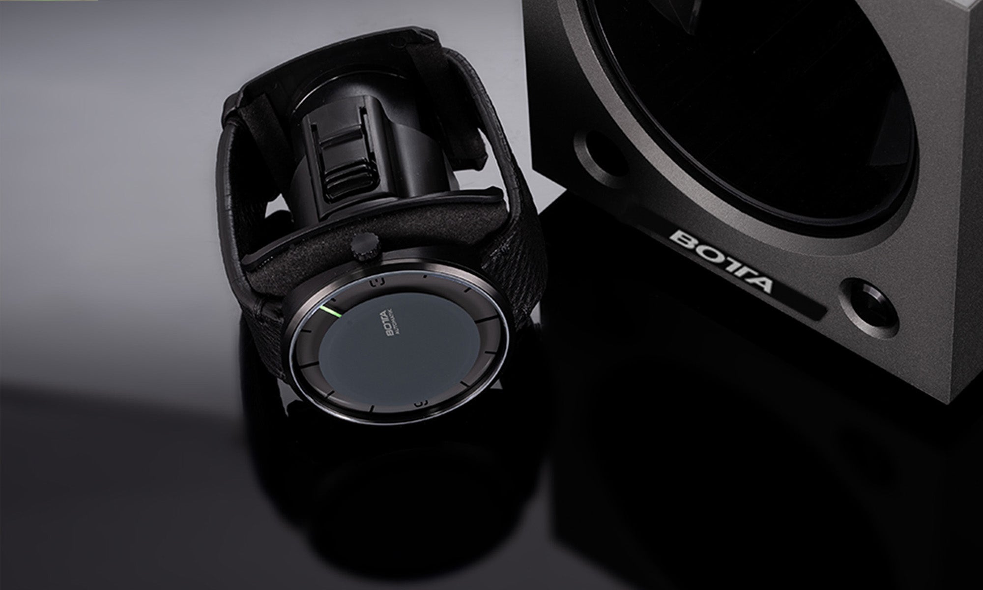 Das Bild zeigt den BOTTA Uhrenbeweger für 2 Uhren in Detailansicht mit entnommener Uhrenhalterung. Eine Designer-Armbanduhr mit schwarzem Lederband und minimalistischer Einzeigeruhr liegt in der Halterung, die in den Beweger eingesetzt wird. Rechts im Bild ist das elegante, kantige Gehäuse des Uhrenbewegers mit BOTTA-Logo erkennbar. Hochwertige Verarbeitung, sichere Aufbewahrung und praktische Handhabung – ideal für alle, die einen stilvollen Uhrenbeweger kaufen oder bestellen möchten.