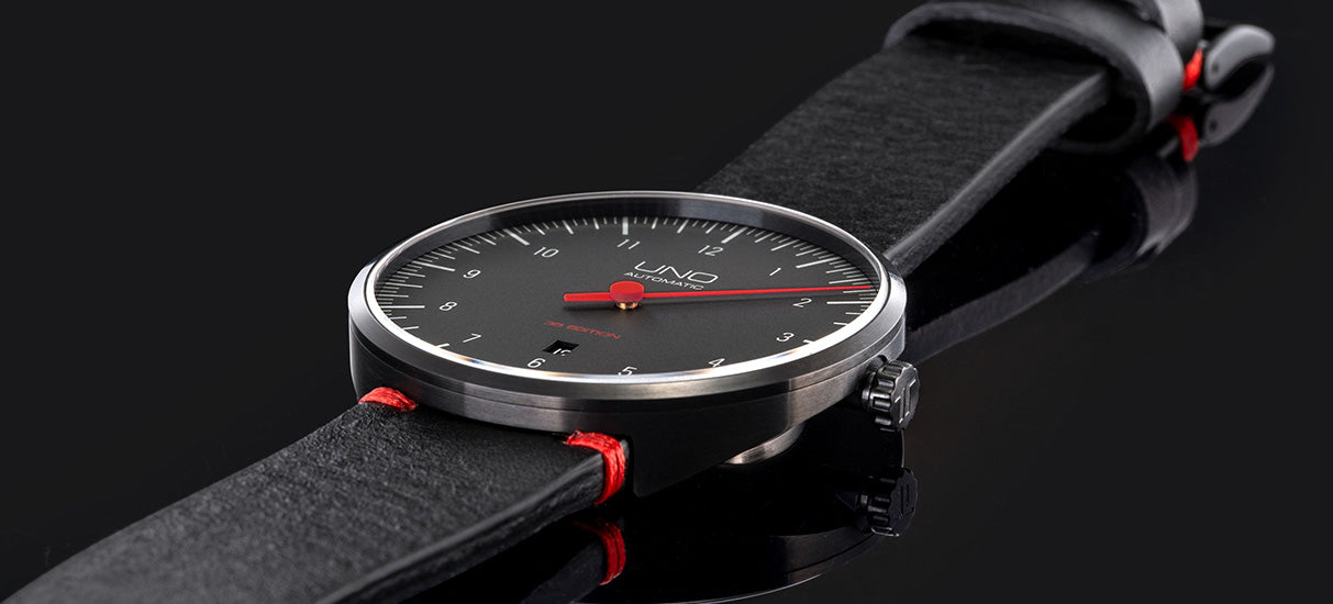 Abgebildet ist die UNO 35 Edition von BOTTA Design in der Ausführung mit schwarzem Zifferblatt und auffälligen roten Details. Diese Automatikuhr zeigt die Zeit mit nur einem Zeiger – präzise, reduziert und intuitiv. Das elegante PVD-beschichtete Edelstahlgehäuse, das doppelt gewölbte Saphirglas und das hochwertige Sellita SW200-1 Automatikwerk unterstreichen die Qualität dieser Designuhr. Eine stilvolle Armbanduhr für Individualisten, die eine exklusive Uhr mit einem Zeiger kaufen oder bestellen möchten.