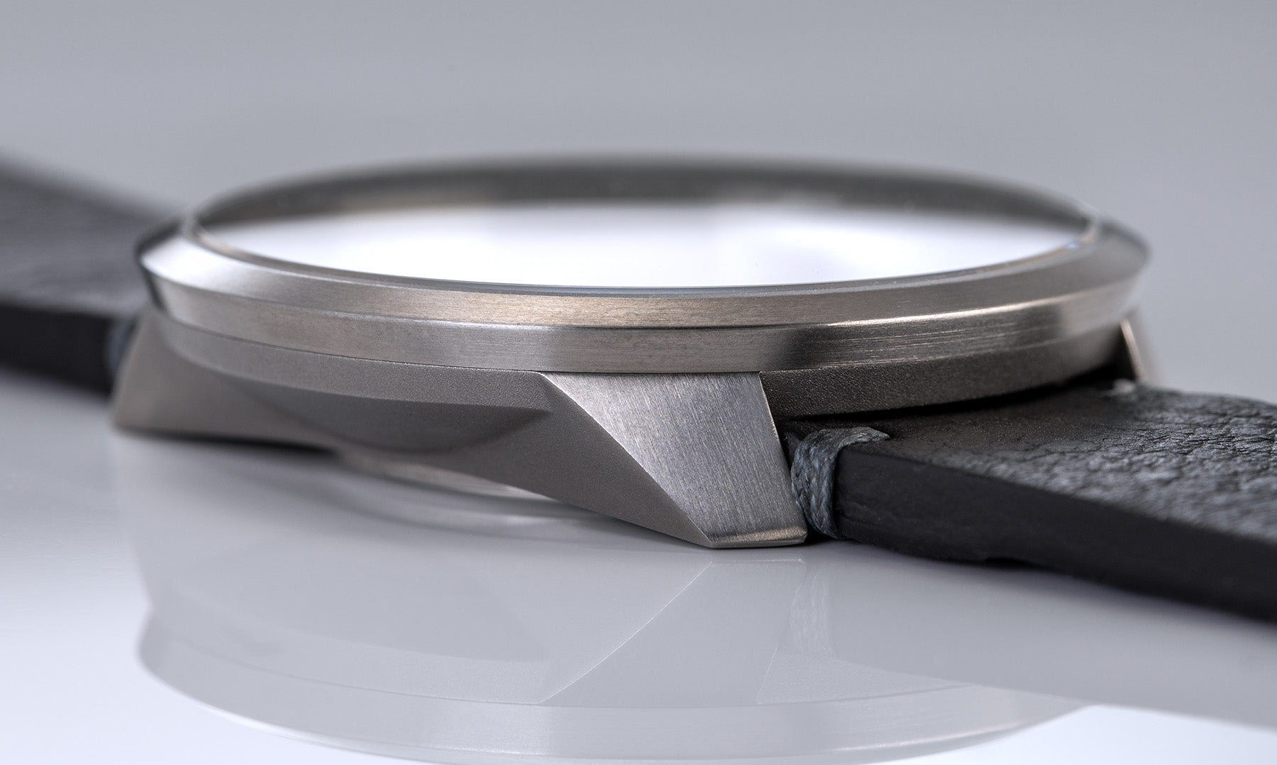 Das Bild zeigt die UNO 24 von BOTTA in einer Nahaufnahme des Gehäuses. Zu sehen ist die präzise gearbeitete Titanarchitektur mit klaren Kanten und satiniertem Schliff sowie das angesetzte schwarze Lederarmband. Diese Armbanduhr verbindet modernes Design mit technischer Raffinesse. Als Einzeigeruhr stellt sie die Zeit im 24h-Format dar – logisch, reduziert und einzigartig. Eine exklusive Designuhr für Anspruchsvolle, die eine besondere Armbanduhr kaufen oder bestellen möchten.