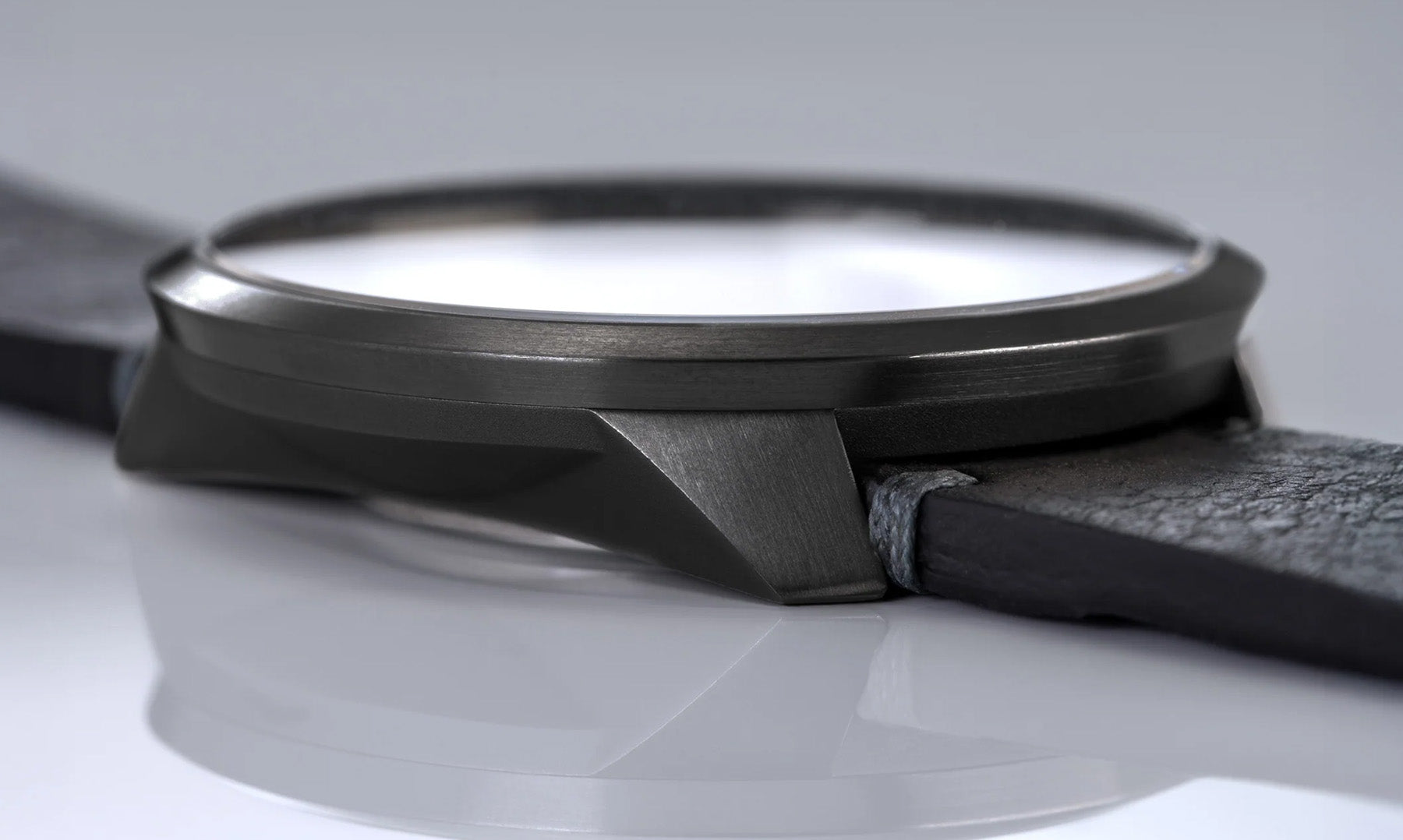 Detailaufnahme des Gehäuses einer BOTTA Armbanduhr im All-Black-Design. Das kantige Tri-Titan-Gehäuse mit matt gebürsteter Oberfläche zeigt die präzise Verarbeitung und hochwertige Materialqualität. Diese 24-Stunden Uhr mit einem Zeiger ist eine exklusive Einzeigeruhr, die technisches Können und minimalistisches Design vereint. Eine hochwertige Armbanduhr Made in Germany. 