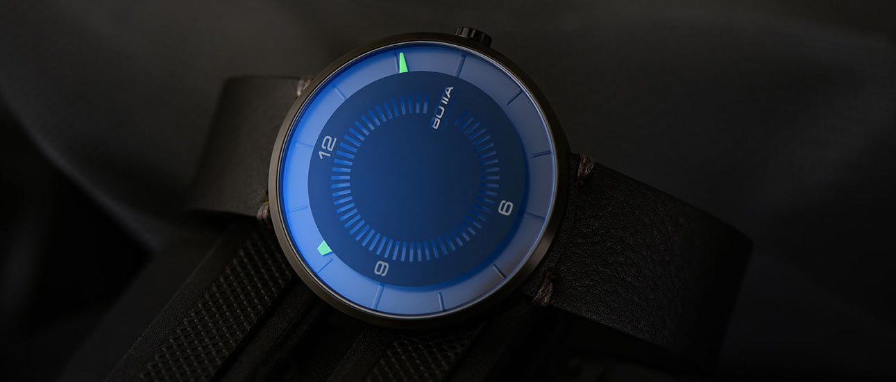Die BOTTA CLAVIUS Automatik 44 mm präsentiert sich hier in einem geheimnisvoll-dunklen Setting, das die futuristische Anmutung der Designuhr unterstreicht. Das Saphirglas schimmert bläulich, während die grünen Leuchtmarkierungen für präzise Ablesbarkeit sorgen. 